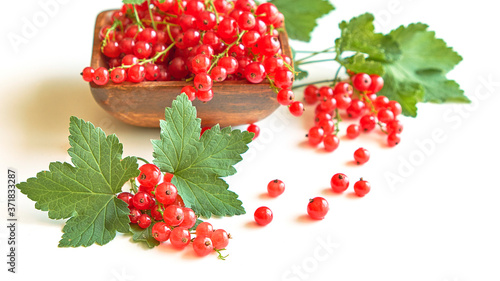 fresh red currant in a wooden bowl isolated on white background. summer harvest of vitamins.