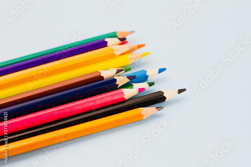 Bright colored assorted pencils on a light blue background. View from above. Place for text.