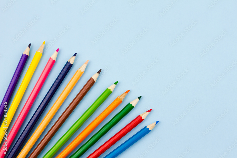 Colored colorful pencils on a light blue background. Place for your text. View from above. Education concept.