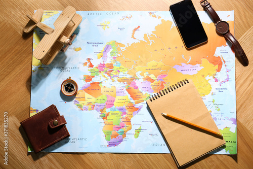 Flat lay composition with world map and different items on wooden background. Trip planning