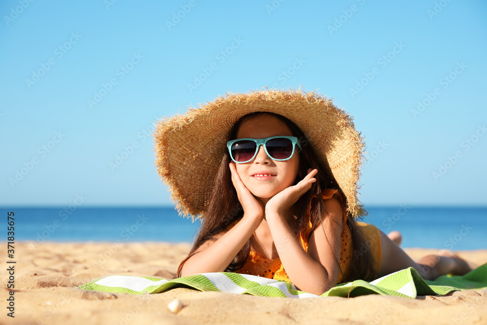 Cute little child lying at sandy beach on sunny day