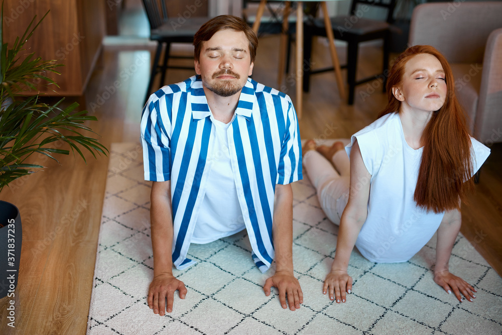 Fototapeta premium portrait of couple stretching before yoga, young man and woman in domestic wear going to practice yoga at home