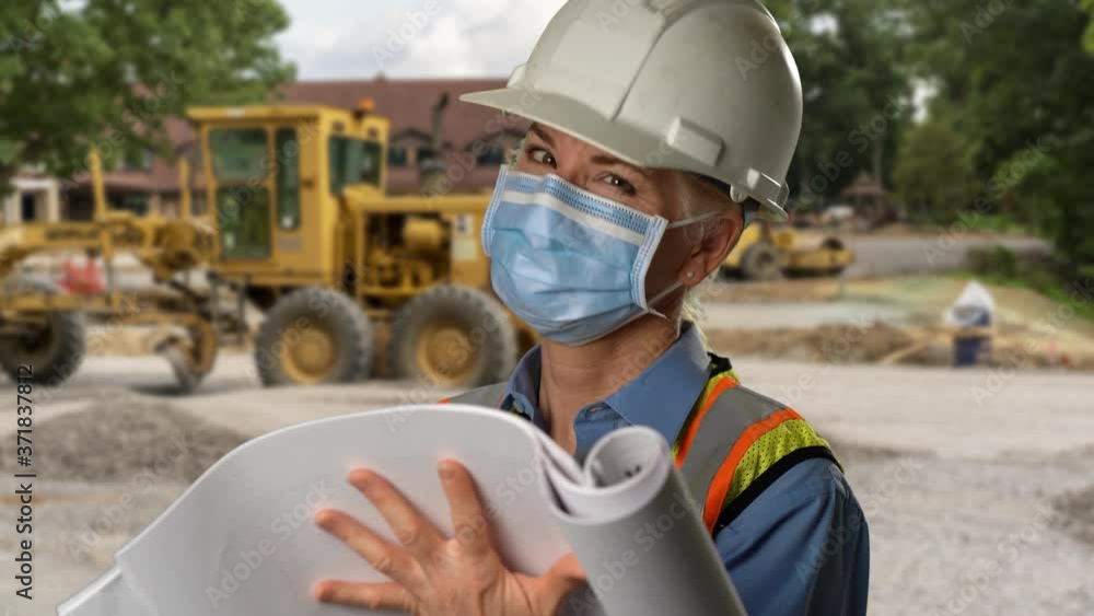 Portrait of woman engineer architect on construction site wearing medical face mask working on blueprints and smiling at camera wearing hard hat and green reflective safety vest. Portrait of woman engineer architect on construction site wearing medical face mask working on blueprints and smiling at camera wearing hard hat and green reflective safety vest.