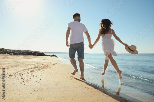 Young couple running on beach near sea. Honeymoon trip