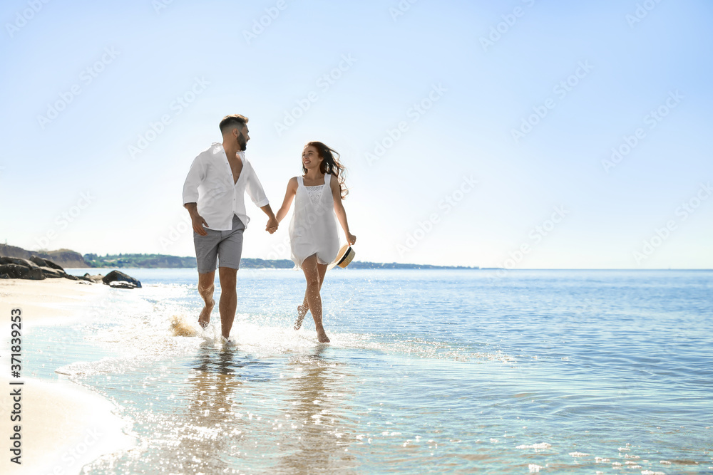 Happy young couple running on beach near sea. Honeymoon trip