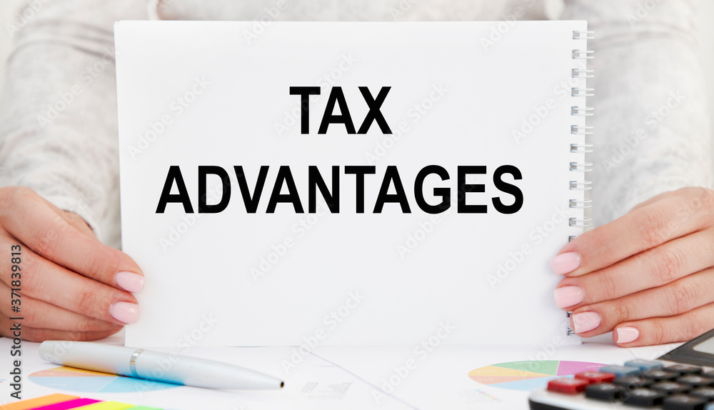 The girl holds a card with the inscription TAX ADVANTAGES on her hand. A business concept.