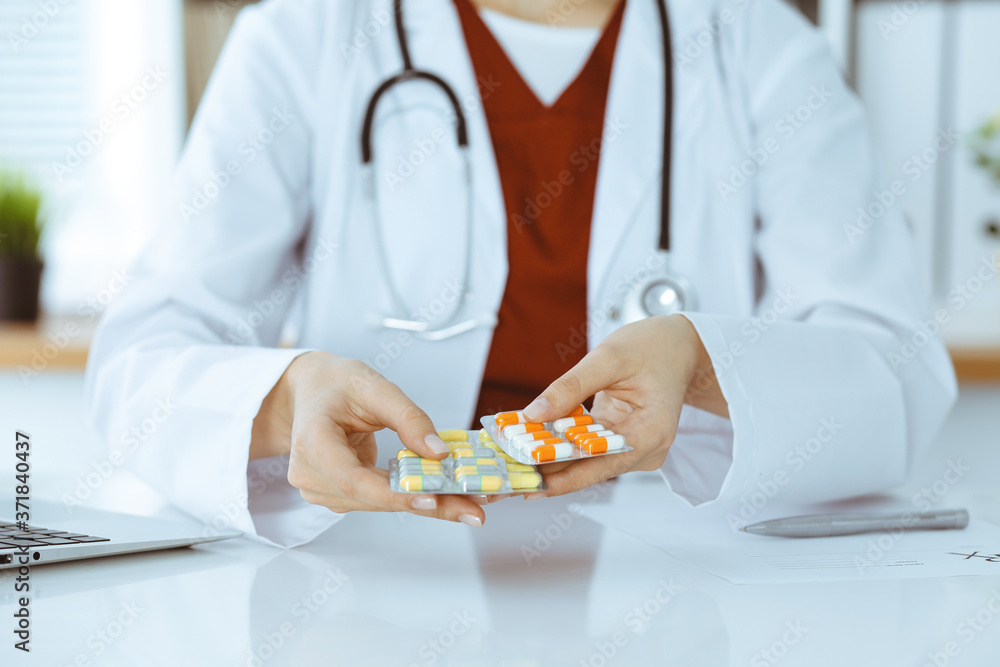 Unknown woman-doctor offering pack of different tablet blisters, close-up. Medicine concept Unknown woman-doctor offering pack of different tablet blisters, close-up. Medicine concept