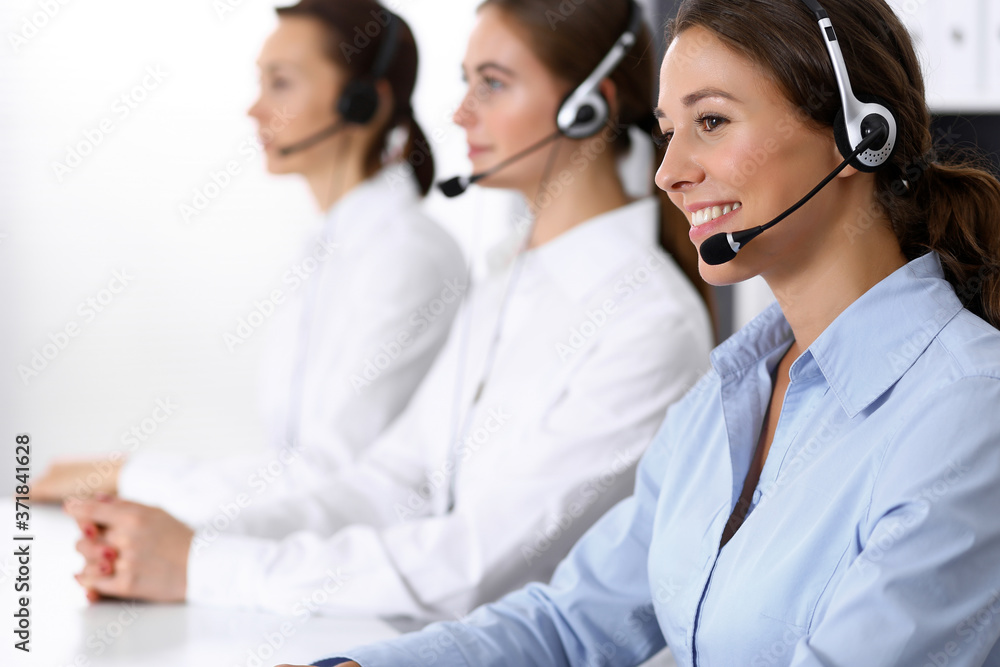Call center. Group of operators at work. Focus at beautiful business woman in headset Call center. Group of operators at work. Focus at beautiful business woman in headset