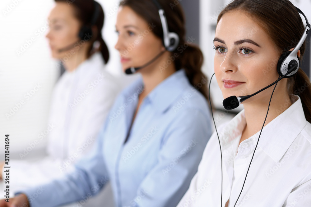 Call center. Group of operators at work. Focus on beautiful business woman in headset Call center. Group of operators at work. Focus on beautiful business woman in headset
