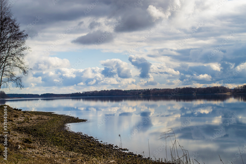 Rocky bank of the Daugava River near Riga. Picturesque view. The nature of Latvia. Beautiful clouds in the blue sky and reflected in the water.