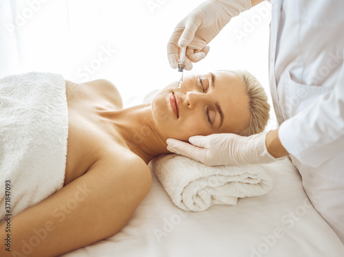 Beautician doctor hands doing beauty procedure to female face with syringe. Cosmetic medicine and surgery, beauty injections concept
