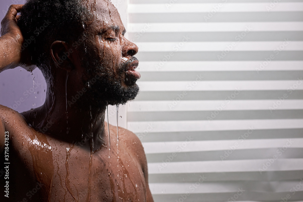 Fototapeta premium middle aged man in shower cubicle, taking a shower alone. he stands with eyes closed, skincare in the morning