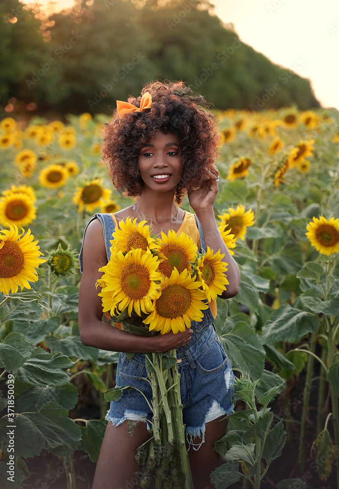 Happy young black woman walks in the sunflower field. Smiling dark ...