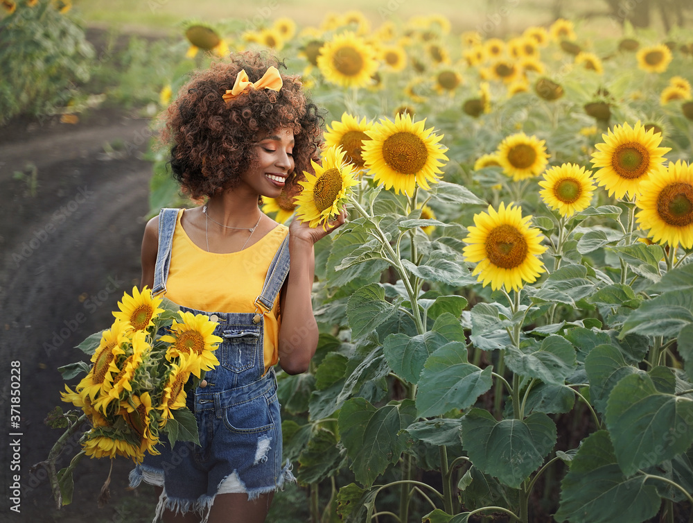 Happy young black woman walks in the sunflower field. Smiling dark ...