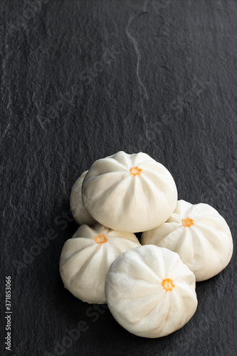 Steamed bao buns with delicious filling on black stone background