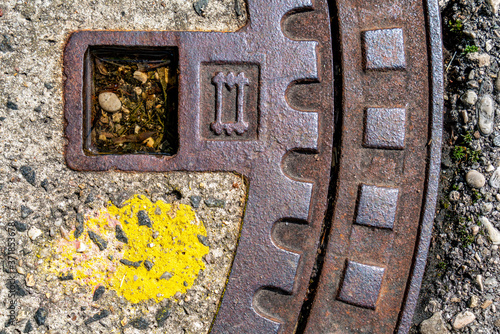 Detail eines Kanaldeckels mit gelber Farbe