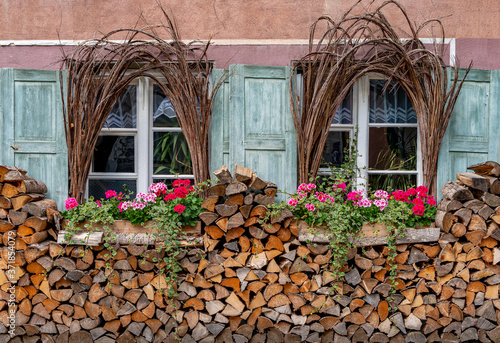 Romantische Fenster-Fassade mit Blumen und Holzscheiten photo
