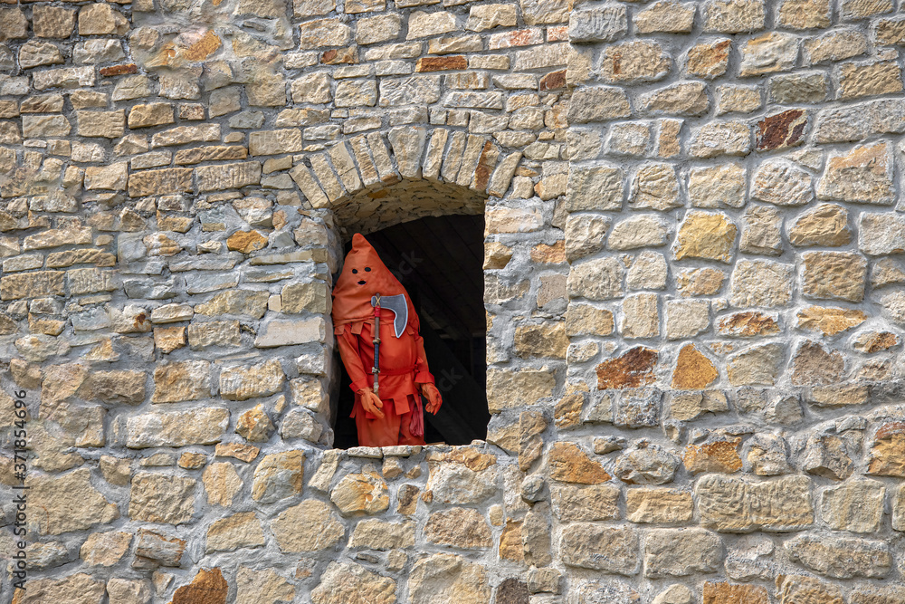 an executioner dressed in red standing in the window of a  castle