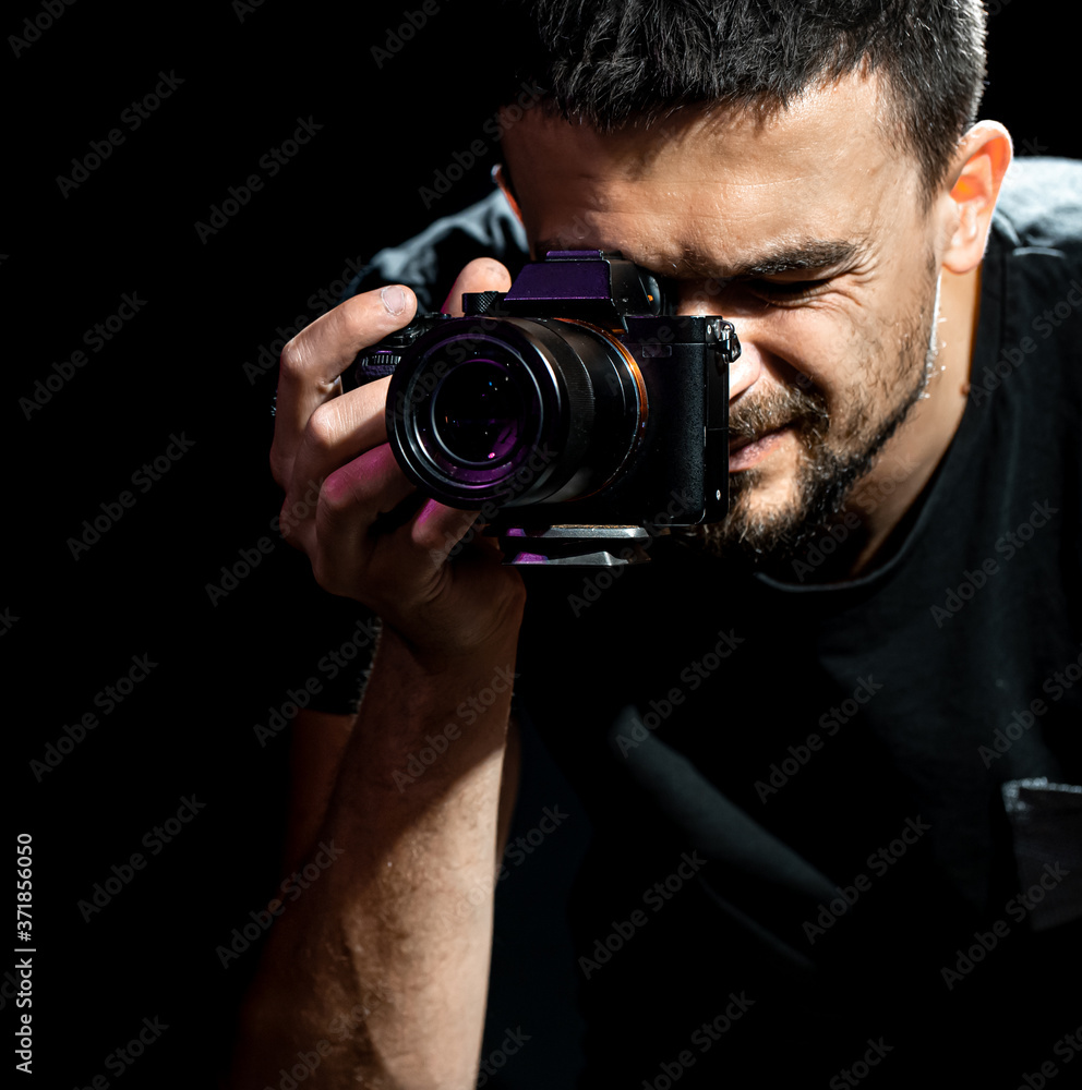 The person is holding a camera and is set up for shooting. The photographer looks into the camera's viewfinder and takes pictures. Object on a black background. The person is holding a camera and is set up for shooting. The photographer looks into the camera's viewfinder and takes pictures. Object on a black background.