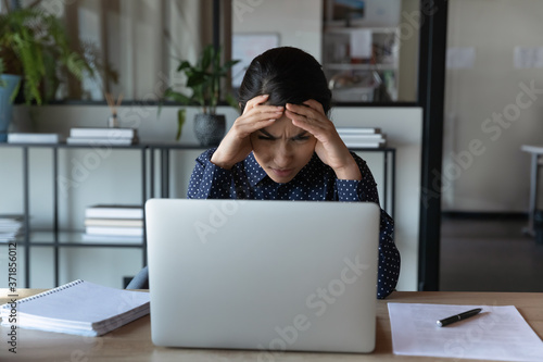 Tableau sur toile Stressed young indian ethnicity businesswoman stuck with hard task, looking at computer screen, Confused millennial female multiracial overload employee suffering from head ache, workaholic concept