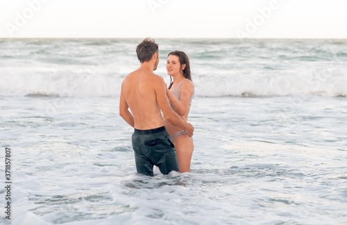 Exotic romantic vacation concept. Young man and woman in the water look at each other
