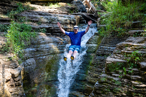 Φωτογραφία Caucasian male on rock waterslide into Devils bathtub in Spearfish Canyon of the