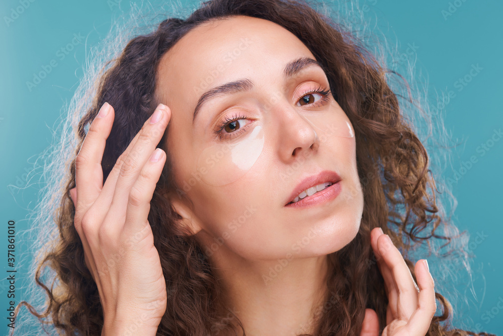 Fototapeta premium Young gorgeous brunette woman with undereye patches touching temple