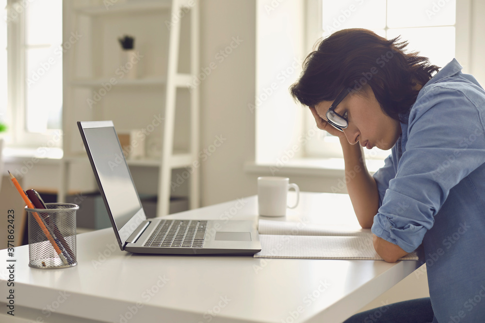 Exhausted young woman working on difficult task in front of laptop at home office. Freelancer feeling tired at workplace Exhausted young woman working on difficult task in front of laptop at home office. Freelancer feeling tired at workplace