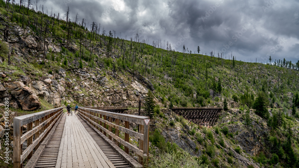 Biking over the Wooden Trestle Bridges of the abandoned Kettle Valley Railway in Myra Canyon near Kelowna, British Columbia, Canada Biking over the Wooden Trestle Bridges of the abandoned Kettle Valley Railway in Myra Canyon near Kelowna, British Columbia, Canada
