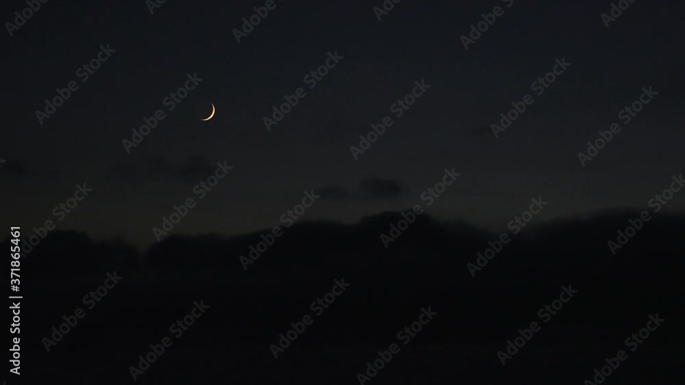 Crescent moon above dark sky clouds passing by wide Lake Huron Ontario Crescent moon above dark sky clouds passing by wide Lake Huron Ontario