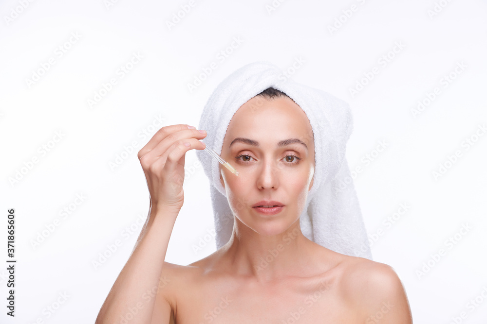 Young woman with white towel on head going to apply rejuvenating serum on face Young woman with white towel on head going to apply rejuvenating serum on face