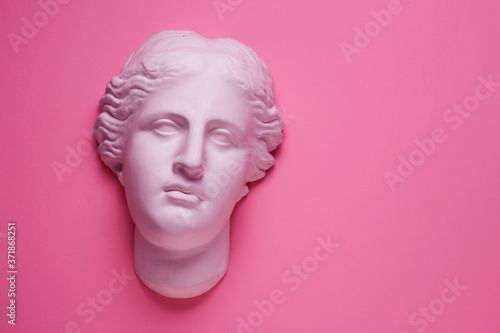 Aphrodite head plaster sculpture on pink background. Beauty and skin care concept, flat lay