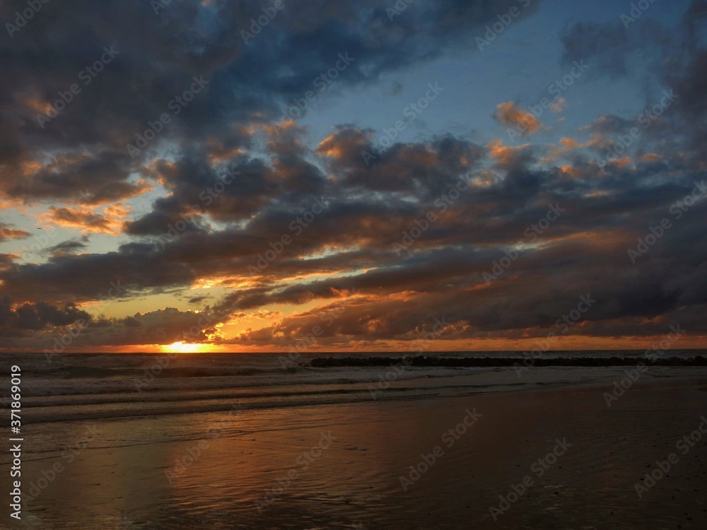Sun sets behind the clouds into the sea Sun sets behind the clouds into the sea