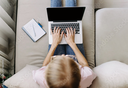 Fotografie Top view of a young woman with a computer on her lap
