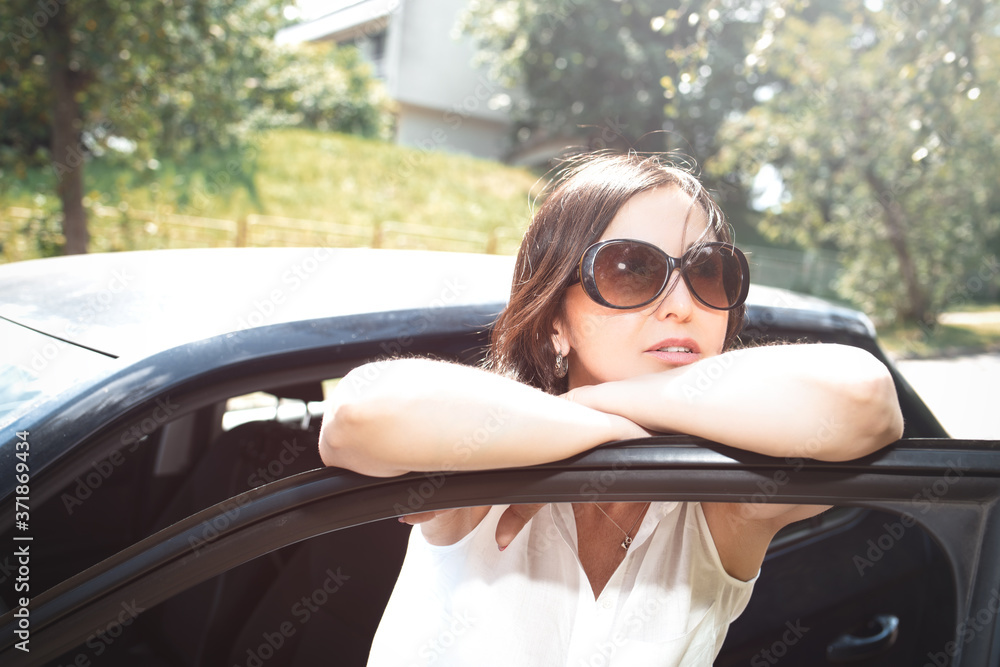 Smiling woman in sunglasses looking out the car