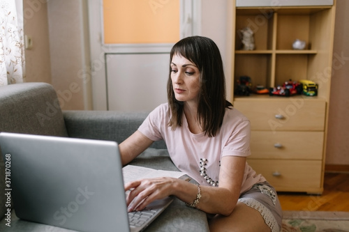 Woman with the phone in hand using laptop at home, girl shopping or chatting online in social network, having fun, watching movie, freelancer working on computer project.