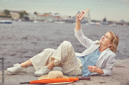 Beautifaul mature lady takes photos near river. photo