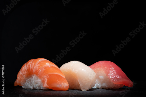 Japanese sushi set with salmon, tuna and perch on a black stone background, copy space photo