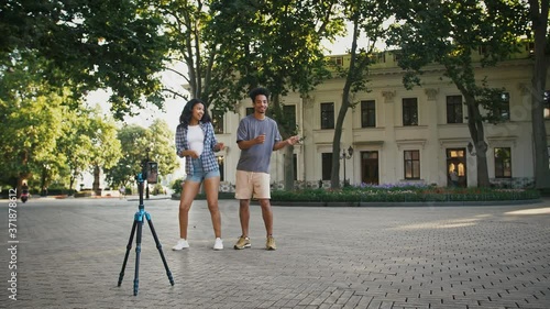 African american couple making videos for social network. Smiling and dancing in front of cellphone fixed on tripod photo