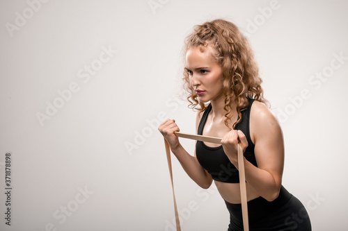 Young sportswoman with blond curly hair making effort while exercising