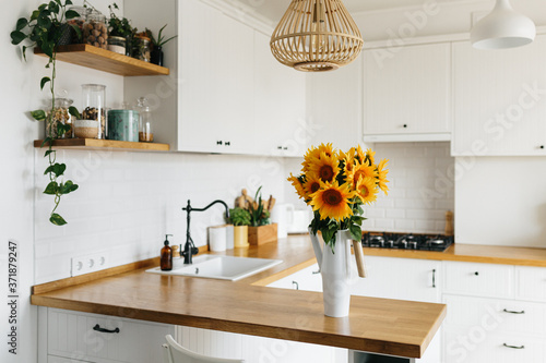 sunflowers bouquet in vase on the kitchen. View on white simple modern kitchen in scandinavian style