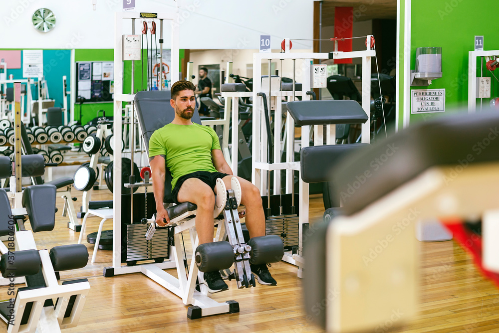 Young sportsman almost shouting when doing leg extension with heavy weight Young sportsman almost shouting when doing leg extension with heavy weight
