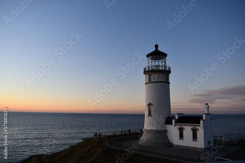 Lighthouse stands along coastal range at dusk.