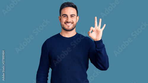 Young handsome man wearing casual clothes smiling positive doing ok sign with hand and fingers. successful expression.