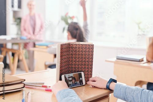 Tableau sur toile Hands of contemporary schoolboy over desk pretending to read book