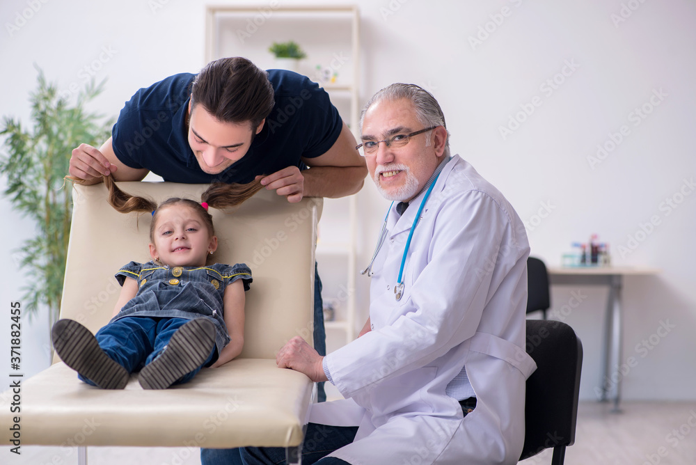 Obraz premium Young father and his daughter visiting old male doctor