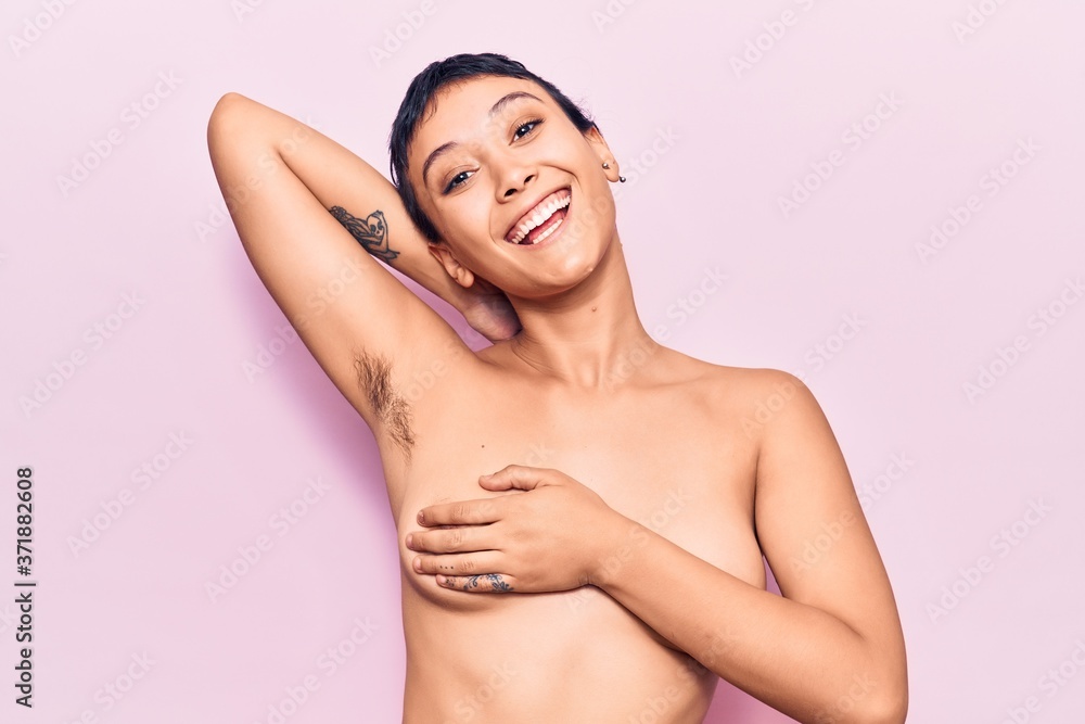 Obraz premium Young beautiful woman shirtless smiling happy. Standing with smile on face showing hairy armpit over isolated pink background