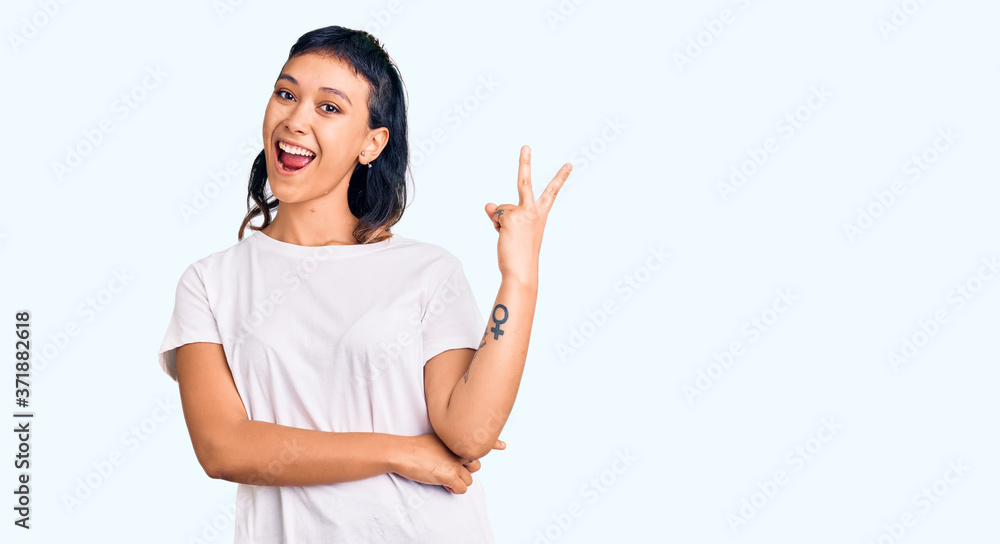 Young woman wearing casual clothes smiling with happy face winking at the camera doing victory sign. number two. Young woman wearing casual clothes smiling with happy face winking at the camera doing victory sign. number two.