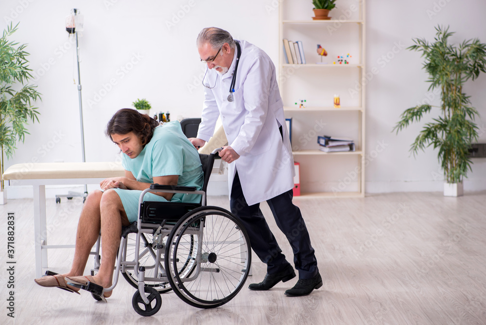Young male patient in wheel-chair and experienced doctor traumatologist Young male patient in wheel-chair and experienced doctor traumatologist