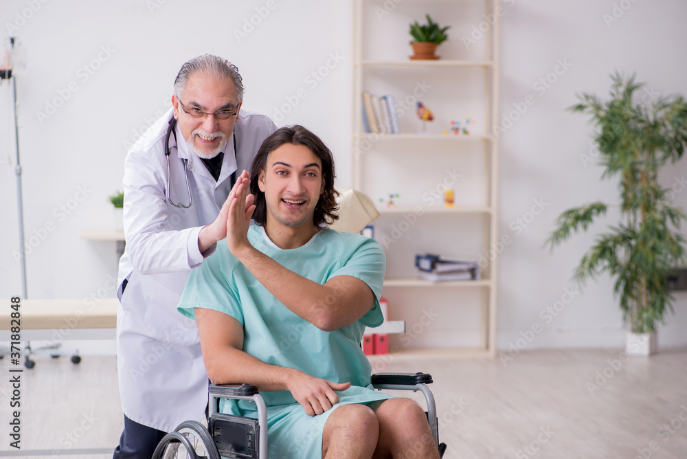 Fototapeta premium Young male patient in wheel-chair and experienced doctor traumatologist